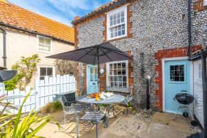 a patio with a table and chairs and an umbrella at Yew Tree Cottage in Blakeney