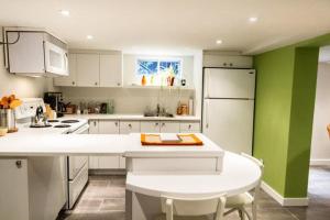 a kitchen with white cabinets and a green wall at L'Adresse Botanique - Studio in Montréal +22 photos