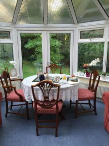 a dining room with a table and chairs and windows at Kingswood Cottage in Lyndhurst