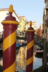 due pali a strisce in un canale con un ponte di Hotel Palazzo Abadessa a Venezia
