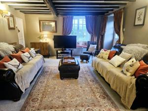 a living room with couches and a flat screen tv at Holly Cottage in Hutton le Hole