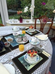 a table with plates of food and a bowl of fruit at Kingswood Cottage in Lyndhurst