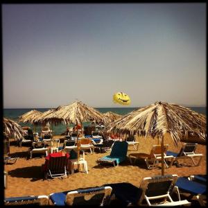 a bunch of chairs and umbrellas on a beach at Heraklion-Pinelopi Apartment in Ayía Marína