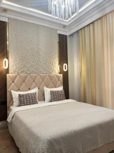 a bedroom with a large bed and a chandelier at Luxury apartment Astana Arena in Astana