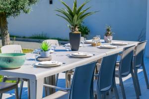 a long white table with chairs and glasses and plants at magnifique villa avec piscine - 8 personnes - paracou in La Chaume