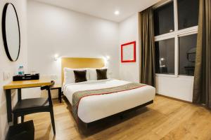 a hotel room with a bed and a desk and window at Super townhouse moosapet Rcc Prime in Hyderabad