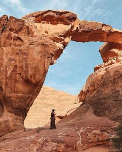 a man standing in front of an arch in the desert at Wadi Rum safari camp in Wadi Rum +25 photos