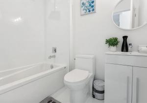 a white bathroom with a toilet and a bath tub at Entire Luxury Suite 4mins To Falls in Niagara Falls +12 photos