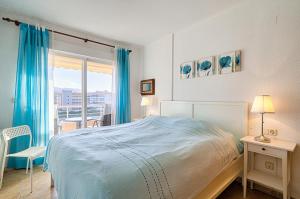 a bedroom with a bed and a balcony with blue curtains at Alborada Golf 13C in L’Alfàs del Pi +21 photos