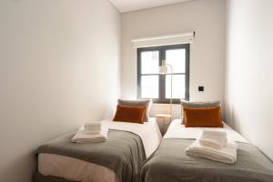 two beds in a room with a window at Baía Terraza Cascais Apartment in Cascais