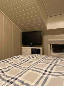a bedroom with a bed and a flat screen tv at Koselig rekkehus, 3 soverom og mye uteplass in Stjoerdal