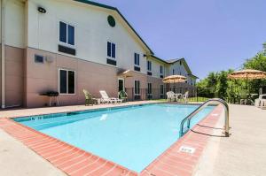 a swimming pool with chairs and umbrellas next to a building at Quality Inn Junction City near Fort Riley in Junction City