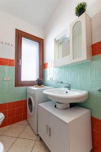 une salle de bain avec un lavabo et une machine à laver dans l'établissement Appartamento Fabio Caletta sul mare, à La Caletta
