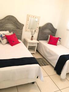 a bedroom with two beds with red pillows and a mirror at Whale Rock Beauty in Margate