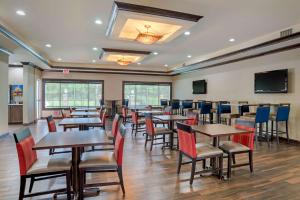 Un restaurante con mesas y sillas y un televisor de pantalla plana. en Comfort Suites Alexandria North, en Alexandria