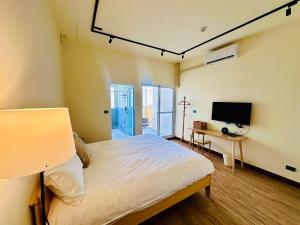 a bedroom with a bed and a flat screen tv at 喝睏H-Khùn酒吧民宿 in Donggang