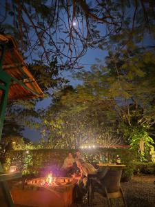 a group of people sitting around a fire pit at night at Camp Temgarh in Lavasa