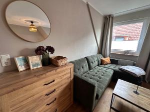 a living room with a green couch and a mirror at Sky & Sand - Endless Sea I Hochwertige, stilvolle Wohnungen, Strandnah, Boxspringbett, mit Garten in Sankt Peter-Ording