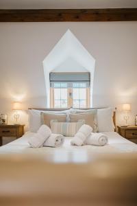 ein weißes Bett mit drei Kissen und einem Fenster in der Unterkunft Sweetheart Cottage - Cosy 2 Bed in The Cotswolds! in Swalcliffe