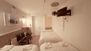 a small room with two beds and two chairs at Warwick Road Rooms in London