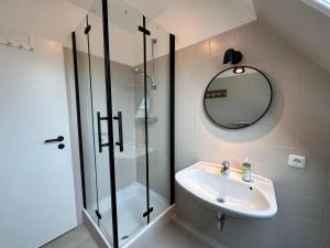 a bathroom with a sink and a shower and a mirror at Sky & Sand - Endless Sea I Hochwertige, stilvolle Wohnungen, Strandnah, Boxspringbett, mit Garten in Sankt Peter-Ording
