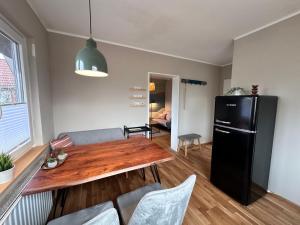 a kitchen with a wooden table and a black refrigerator at Sky & Sand - Endless Sea I Hochwertige, stilvolle Wohnungen, Strandnah, Boxspringbett, mit Garten in Sankt Peter-Ording +34 photos
