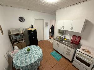 a small kitchen with a table and a refrigerator at Casa rosa in Cruz Alta