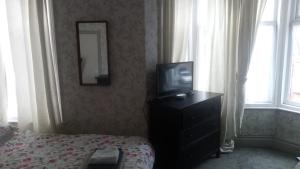 a bedroom with a tv and a dresser with a bed at The New Macleods Guest House in Blackpool