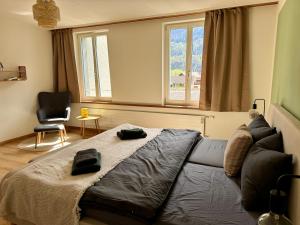 a bedroom with a couch and a chair and windows at Spacious, stylish & central apartment, Great excursions in surrounding area in Meiringen