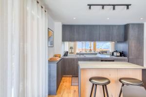 a kitchen with gray cabinets and a counter with stools at Apartment w pool and spa in Champéry