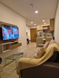 Una sala de estar con un sofá y un televisor en una pared. en Houze 507, en Asunción