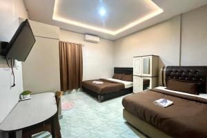 une chambre d'hôtel avec deux lits et une télévision dans l'établissement Gratia Guesthouse, à Jambi