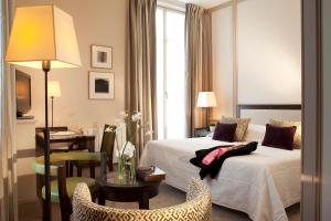 パリにあるホテル ドゥ ラルカードのベッド、テーブル、椅子が備わるホテルルームです。