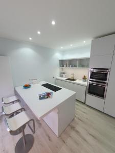 eine weiße Küche mit einer weißen Insel und Stühlen in der Unterkunft Kappeln 333 in Kappeln