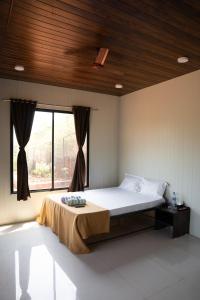 a bedroom with a bed and a large window at Jungle Spring Resort in Ghātkar +15 photos