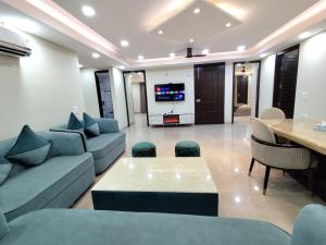 a living room with couches and a table and a television at Homlee-Virasat 3BHK Flat Central DEL-Lift-Parking in New Delhi