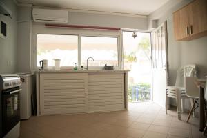 a kitchen with a sink and a large window at Paradise Tolo Beach Apartment in Tolo