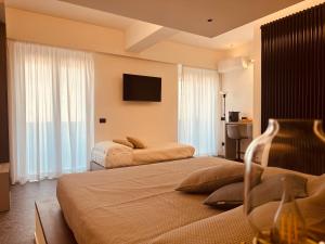 a hotel room with two beds and a flat screen tv at Elegance Rooms Cefalù in Cefalù