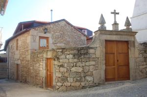 a stone building with two doors and a stone wall at Outros tempos Turismo de Aldeia in Armamar
