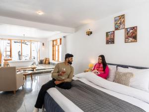 Ein Mann und eine Frau sitzen auf einem Bett in einem Schlafzimmer in der Unterkunft Moustache Koksar Luxuria, Sissu in Khoksar