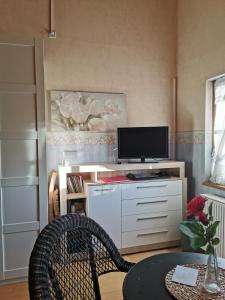 a living room with a desk with a tv and a table at Vreni's Gästezimmer in Himmelried