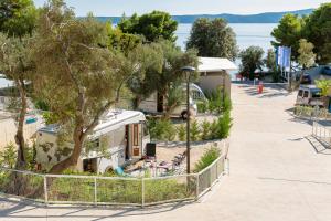 an rv parked in a parking lot next to a tree at Medora Orbis Camping Pitches in Podgora