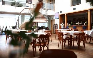 Hotel Atrium في فيشكوف: غرفة طعام مع طاولات وكراسي وشخص في الخلفية