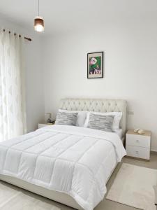 Un dormitorio blanco con una gran cama blanca. en Liqeni i thate apartment, en Tirana