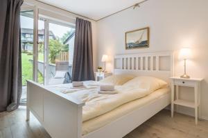 a white bedroom with a large bed and a balcony at Hotel-Restaurant Nordlicht in Kappeln