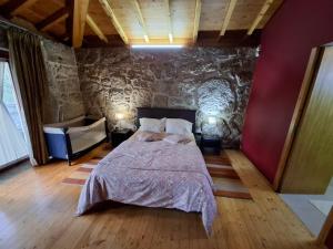 ein Schlafzimmer mit einem Bett und einer Steinwand in der Unterkunft House 3 in Fafe