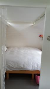 Bett in einem kleinen Zimmer mit weißer Tagesdecke in der Unterkunft Bed & Breakfast Markelo in Markelo