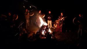 Un gruppo di persone che si aggirano intorno a un falò di notte di Sacred Valley Mystic Tribe a Písac
