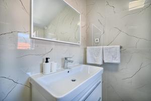 a white bathroom with a sink and a mirror at 3rd Floor Apartman in Kaštela +25 photos