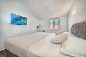 a white bedroom with a large bed with a tv on the wall at 3rd Floor Apartman in Kaštela